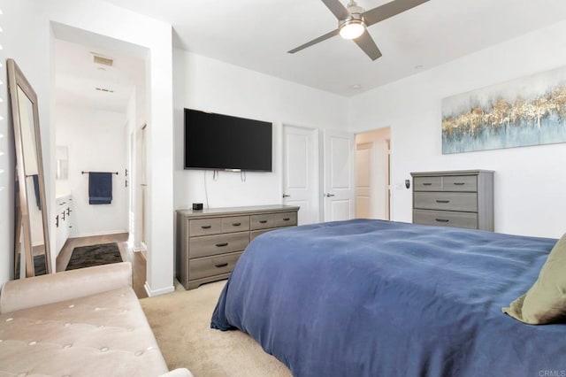 bedroom featuring a ceiling fan, light colored carpet, connected bathroom, and baseboards