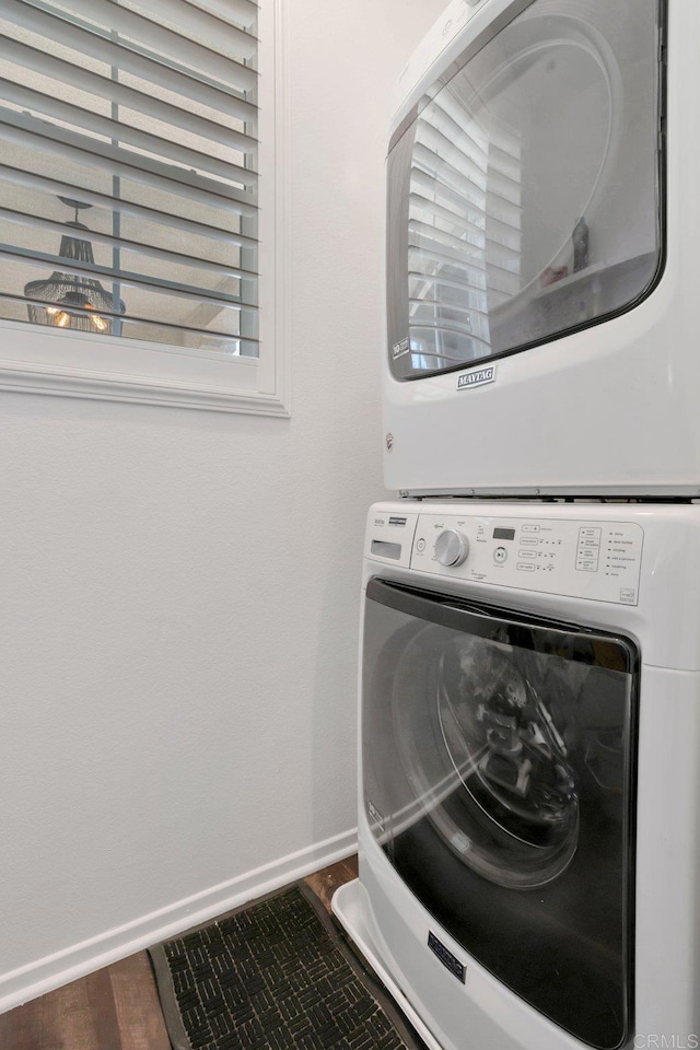 washroom with laundry area, baseboards, dark wood finished floors, and stacked washing maching and dryer