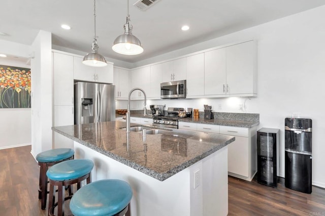 kitchen with a center island with sink, stainless steel appliances, visible vents, dark wood-type flooring, and white cabinets