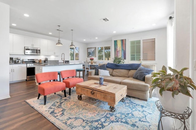 living room with dark wood finished floors, visible vents, and recessed lighting