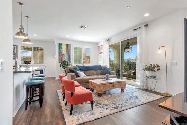 living area featuring baseboards, visible vents, dark wood-type flooring, and recessed lighting