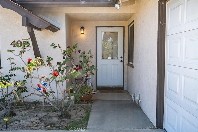 view of exterior entry featuring a garage and stucco siding