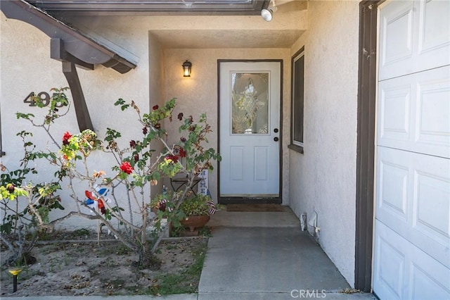 property entrance with stucco siding and a garage