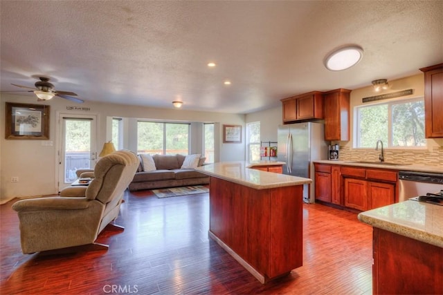 kitchen with a center island, light countertops, dark wood-type flooring, open floor plan, and a sink