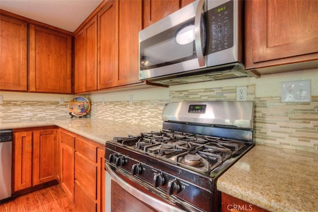 kitchen featuring light stone countertops, tasteful backsplash, and appliances with stainless steel finishes