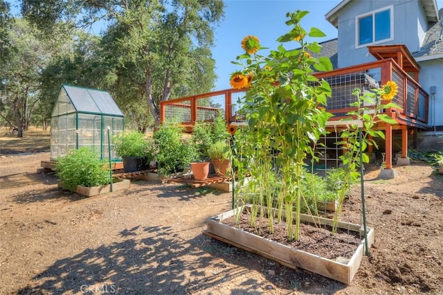 view of play area with an outbuilding, a greenhouse, and a vegetable garden