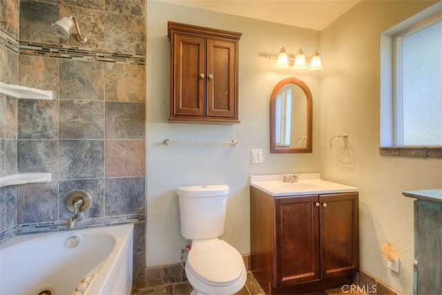 bathroom featuring toilet, a jetted tub, vanity, and baseboards