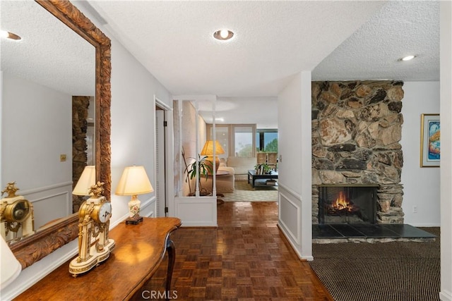 corridor featuring a wainscoted wall, a decorative wall, and a textured ceiling