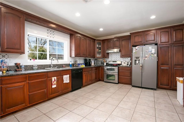 kitchen featuring under cabinet range hood, a sink, appliances with stainless steel finishes, decorative backsplash, and glass insert cabinets