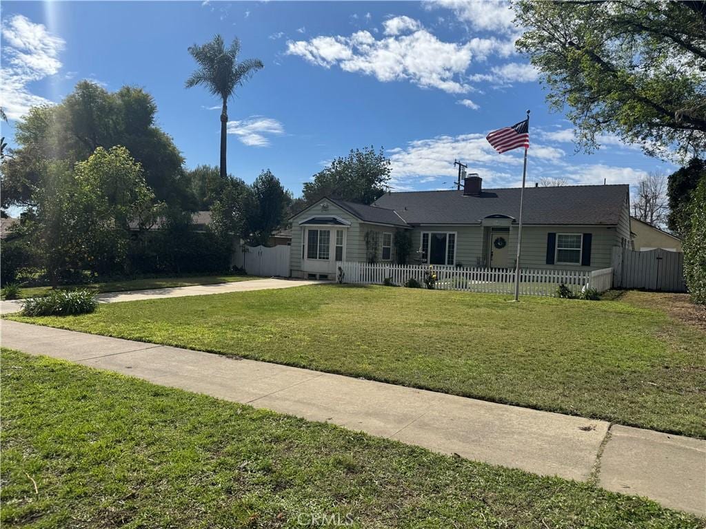 single story home featuring fence and a front lawn