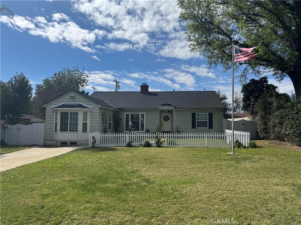 view of front of property featuring a front lawn, a fenced front yard, and a chimney