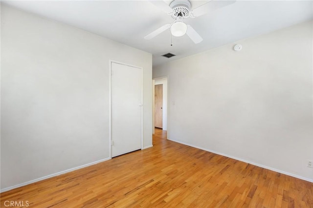 empty room featuring light wood-style floors, baseboards, visible vents, and a ceiling fan