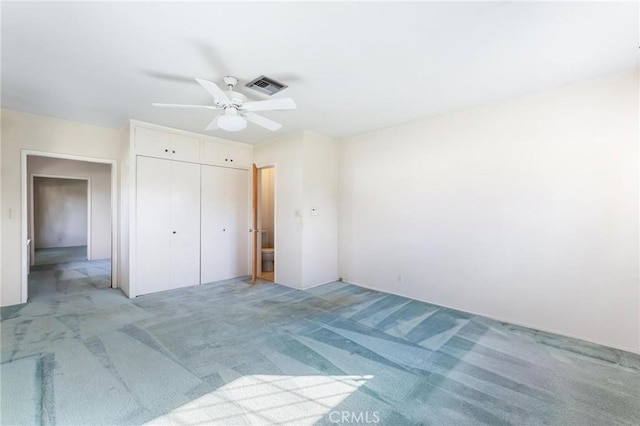 unfurnished bedroom featuring light colored carpet, a closet, visible vents, and ceiling fan