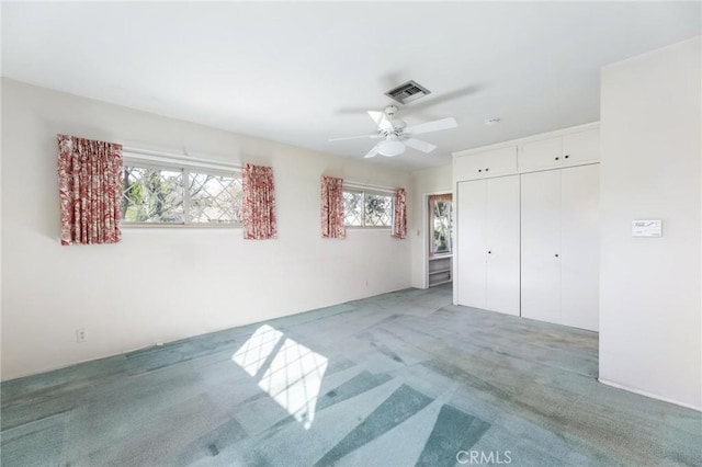 unfurnished bedroom with carpet, a closet, visible vents, and ceiling fan