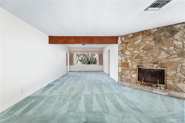 unfurnished living room with carpet, beam ceiling, a fireplace, and visible vents