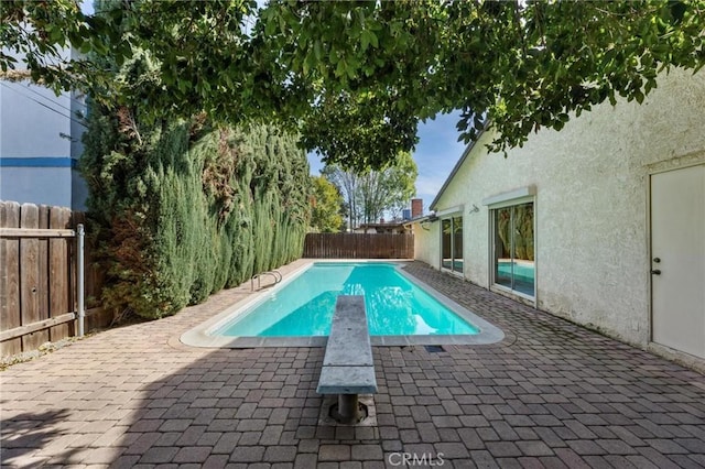 view of swimming pool featuring a diving board, a patio, a fenced backyard, and a fenced in pool