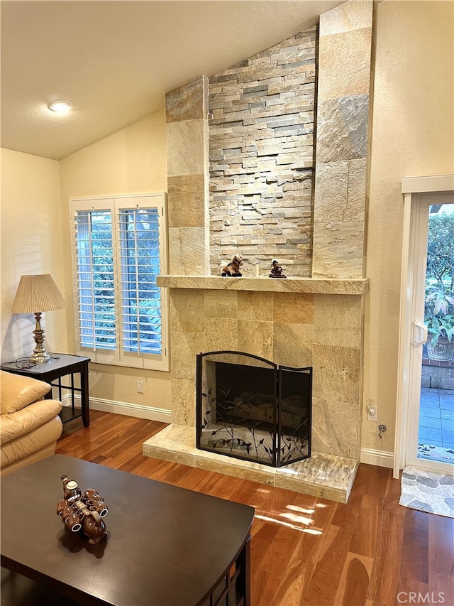 living room featuring a fireplace, baseboards, vaulted ceiling, and wood finished floors