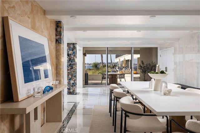 dining space featuring marble finish floor and beamed ceiling