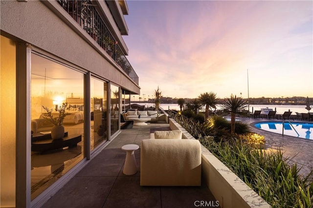 balcony at dusk featuring a water view