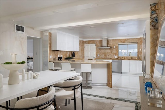 kitchen featuring light countertops, white cabinets, dishwasher, and wall chimney exhaust hood