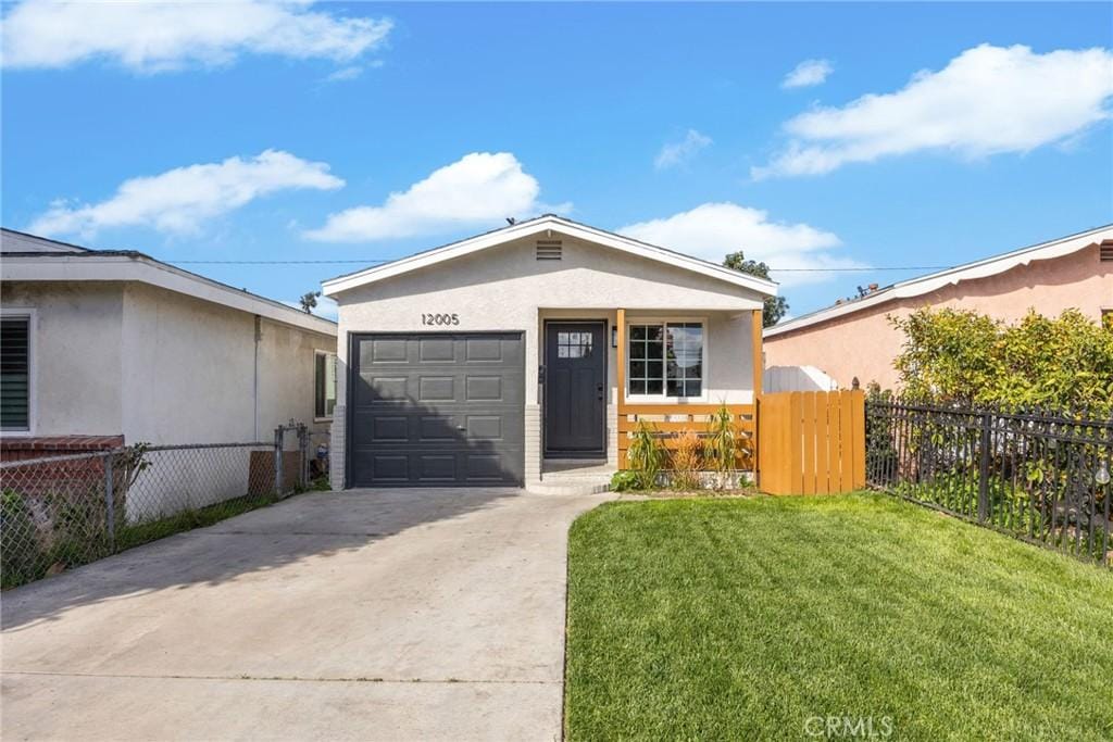 view of front of home with a garage, fence, concrete driveway, stucco siding, and a front yard