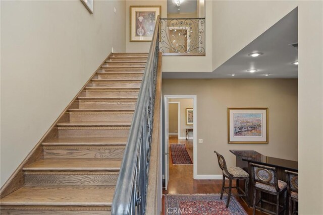 stairs featuring a high ceiling, baseboards, and wood finished floors