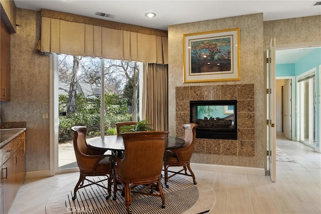 dining area featuring baseboards, visible vents, and a tiled fireplace