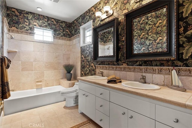 bathroom with double vanity, a sink, toilet, and wallpapered walls