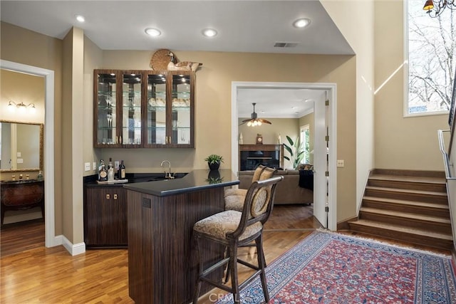 bar featuring visible vents, stairs, wet bar, light wood-style floors, and a sink