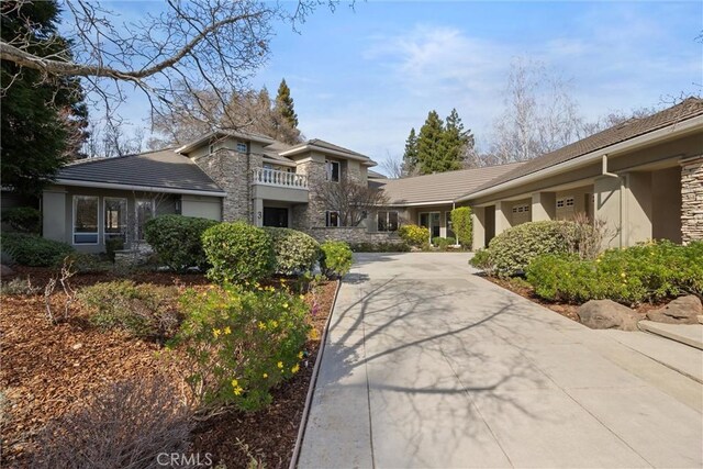 view of front facade with stone siding, driveway, and stucco siding