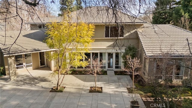 rear view of house featuring a patio area and stucco siding