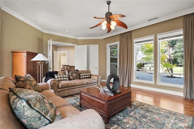 living room with ornamental molding, wood finished floors, visible vents, and a ceiling fan