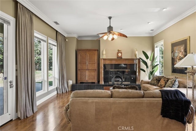 living room featuring visible vents, a ceiling fan, wood finished floors, crown molding, and a high end fireplace