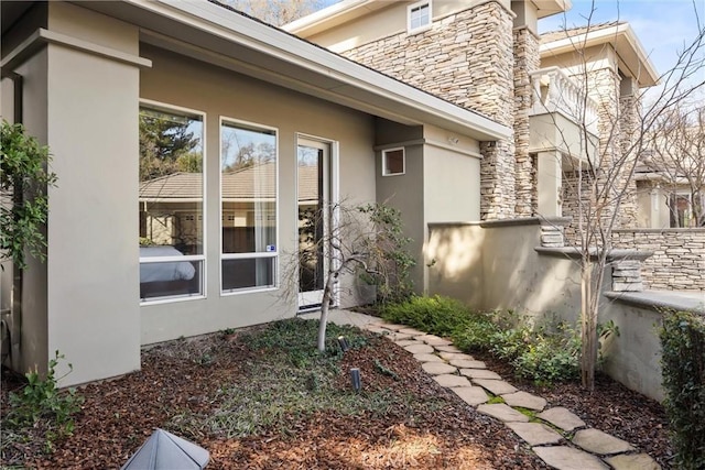 view of side of home featuring stone siding and stucco siding