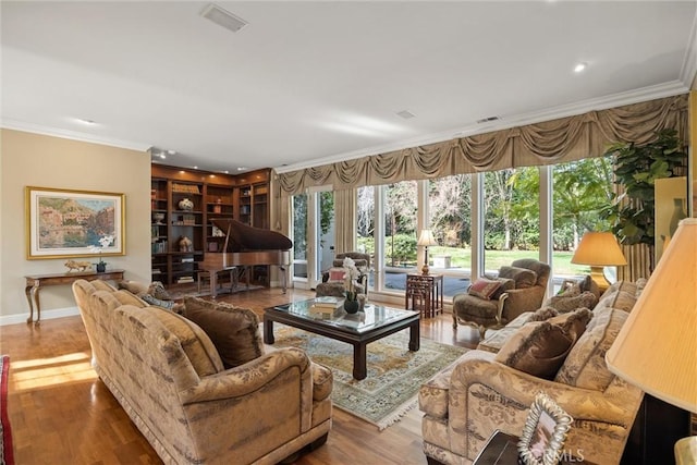 living room with visible vents, baseboards, crown molding, and wood finished floors