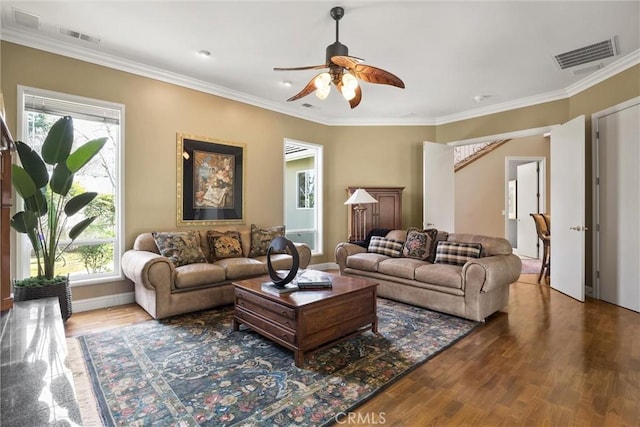 living area featuring a ceiling fan, visible vents, wood finished floors, and ornamental molding