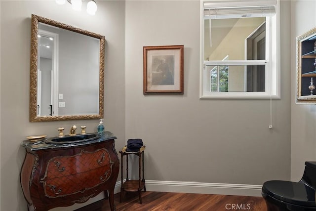 bathroom with toilet, vanity, baseboards, and wood finished floors