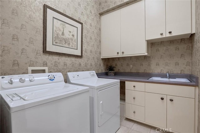 washroom with washing machine and dryer, cabinet space, a sink, and wallpapered walls