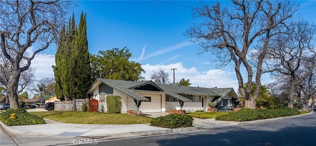 view of front of house with stucco siding, driveway, a front lawn, and fence