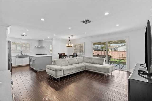 living area featuring dark wood-style floors, crown molding, recessed lighting, visible vents, and a chandelier