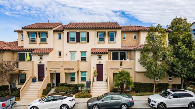 view of front of house with stairway, a tile roof, and stucco siding