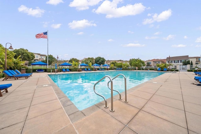 pool with a patio area, a residential view, and fence