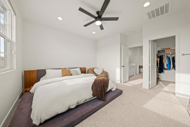 bedroom featuring recessed lighting, light carpet, visible vents, baseboards, and a walk in closet