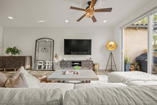 living room featuring baseboards, recessed lighting, a ceiling fan, and light wood-style floors