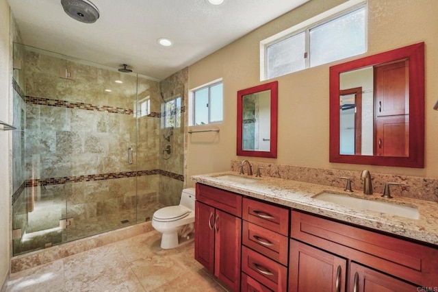 full bath with double vanity, a sink, toilet, and a shower stall