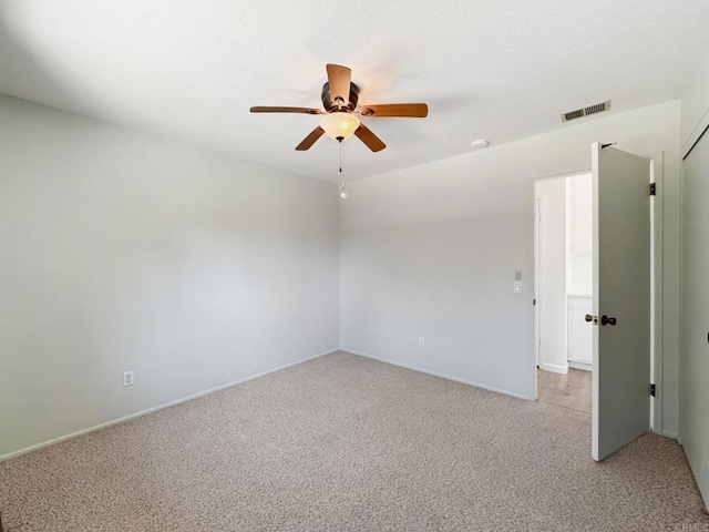 spare room featuring visible vents, a ceiling fan, and light colored carpet