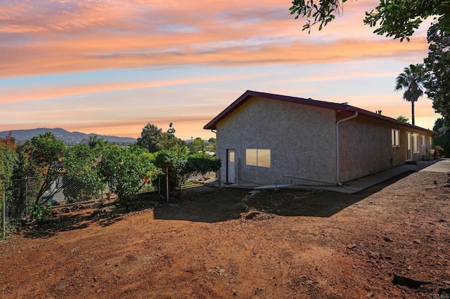 view of side of property featuring a mountain view, fence, and stucco siding