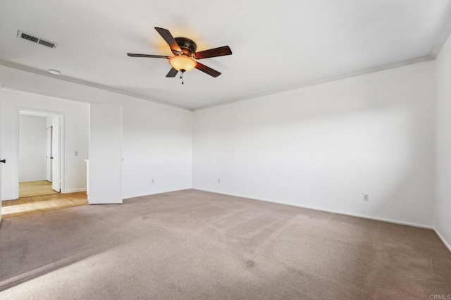 empty room featuring ornamental molding, a ceiling fan, visible vents, and light colored carpet