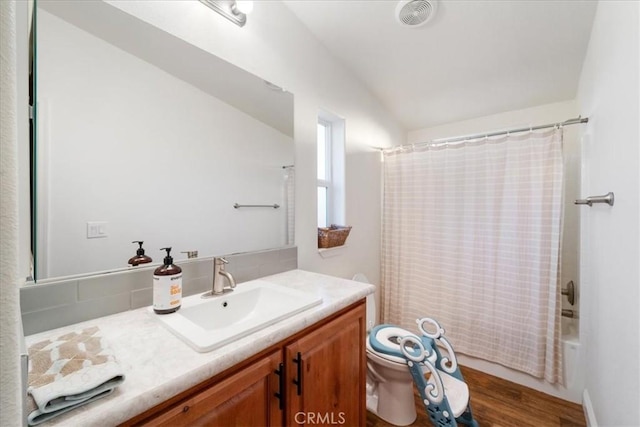 full bath with toilet, wood finished floors, visible vents, vanity, and shower / bath combo with shower curtain