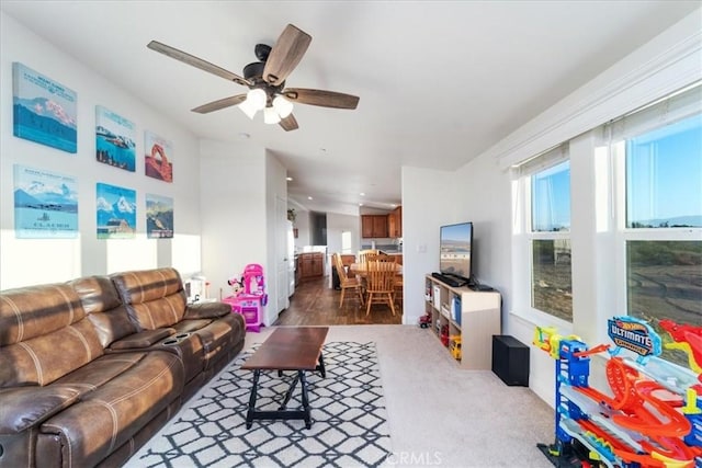 carpeted living area with a ceiling fan